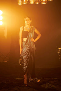 Saia metallic slit saree with an embellished pearl blouse will definitely make you look sassy and elegant in an event.  Tailored to perfection in a metallic fabric, the saree features a slit from the waist level and has an attached palla which creates a great fall.  It comes with a pearl embellished blouse with dori attachments on the back.